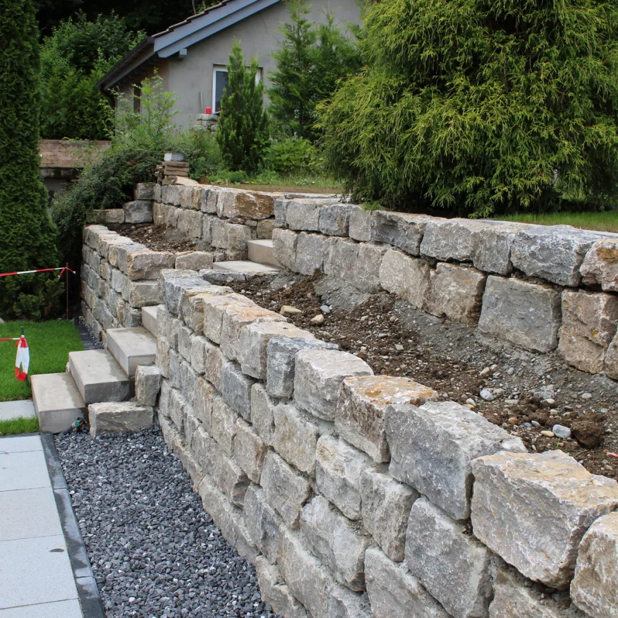 Geschichtete Natursteinmauer als Hangabfangung in einem Privatgarten