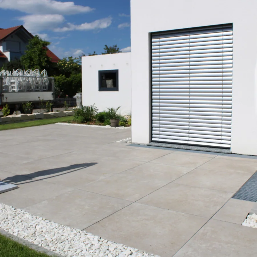 Gleichmäßige Rasenfläche mit angrenzender Pflasterfläche an einem Neubau